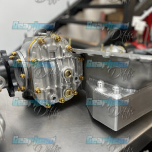 Close-up of a polished GT-R Front Diff Brace Kit (R32/R33/R34/RB 4WB) by Gearhead Diffs on a workbench, “Gearhead Diffs” watermarked across the image. Various diffs and car parts appear in the background.